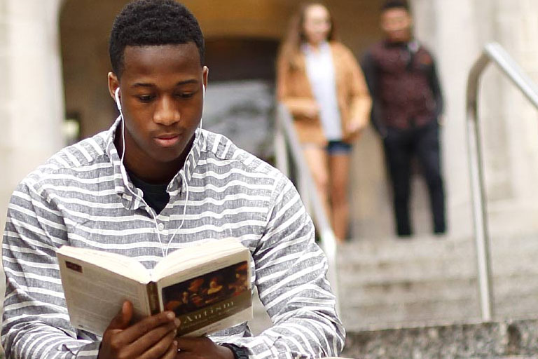 Young male sitting on steps reading.